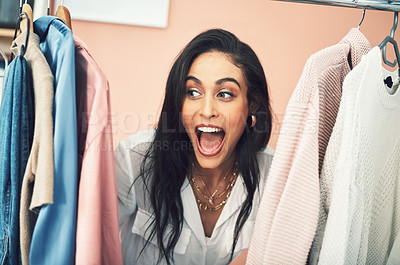 Buy stock photo Shot of a young woman sticking her head in between items on a clothing rail