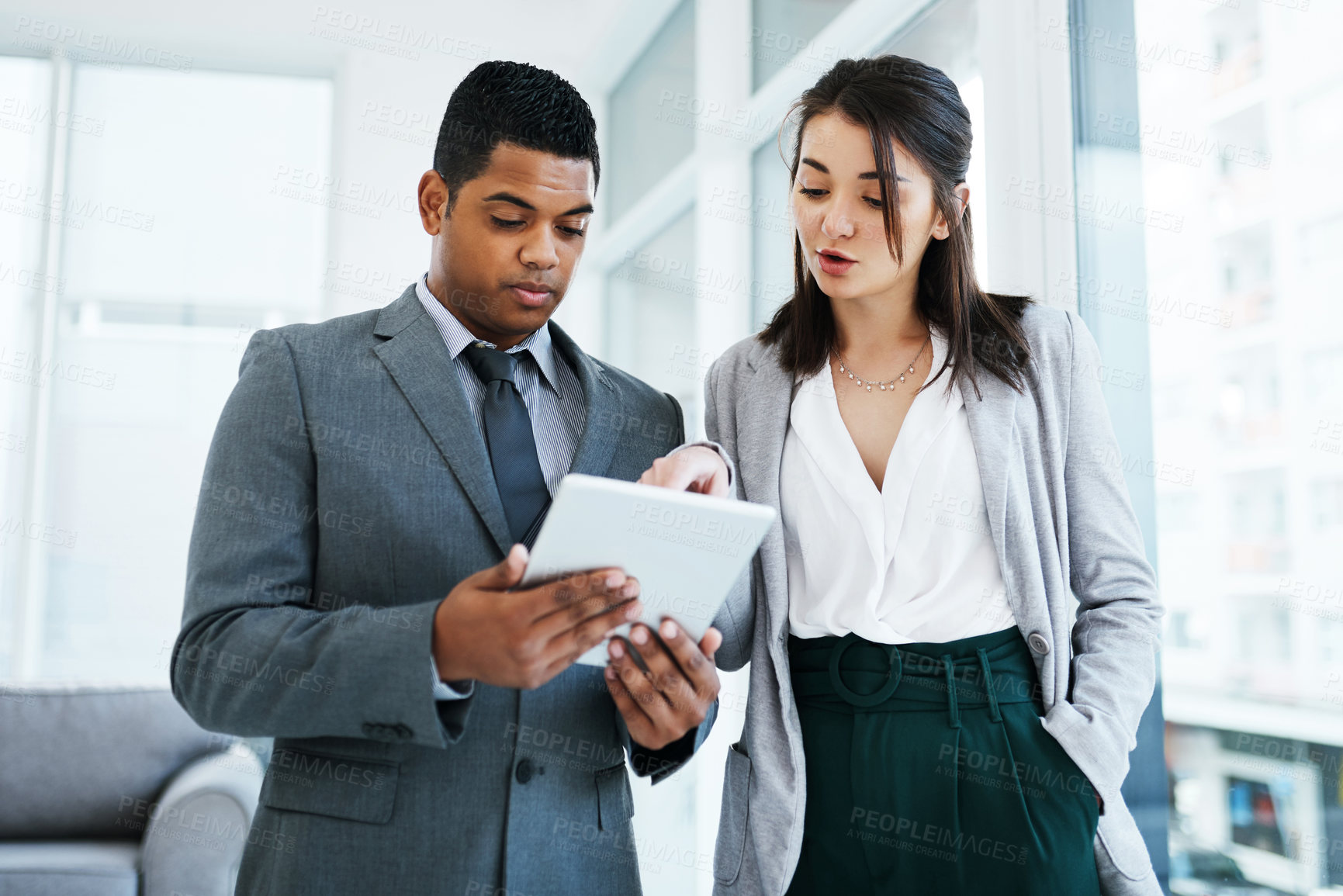 Buy stock photo Shot of a young businessman and businesswoman using a digital tablet in a modern office