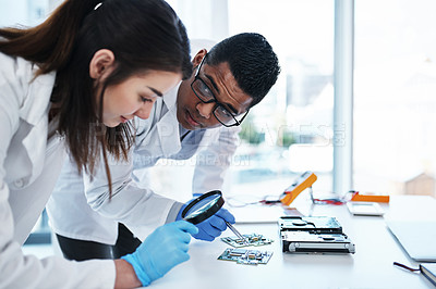 Buy stock photo Shot of a young man and woman repairing computer hardware in a laboratory