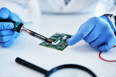 Buy stock photo Shot of a technician using a soldering iron to repair computer hardware in a laboratory