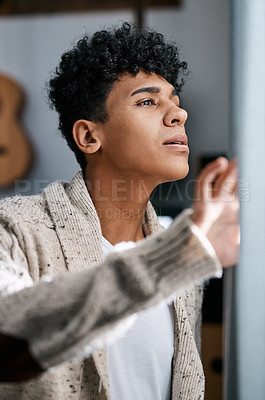Buy stock photo Shot of a young man opening his bedroom curtains in the morning at home