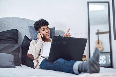 Buy stock photo Shot of a young man using a smartphone and laptop on the bed at home