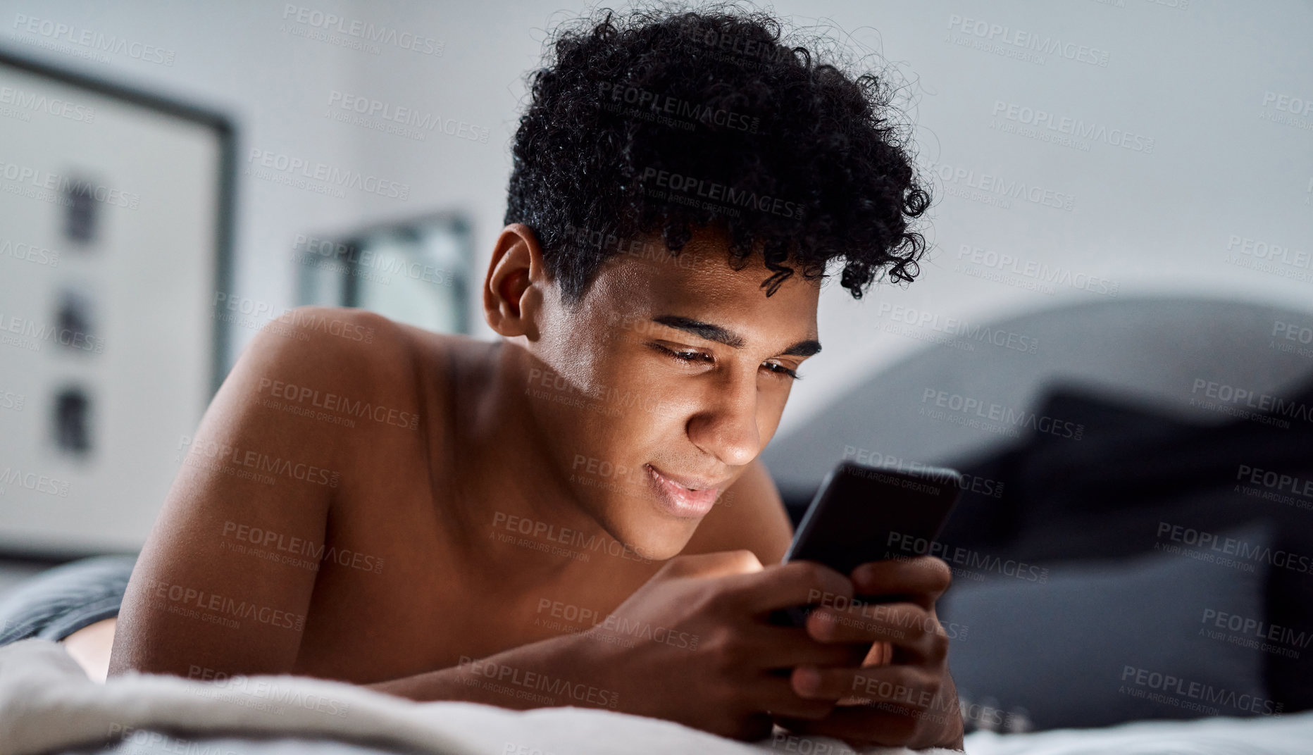 Buy stock photo Teenager, happy and mobile on bed for social media app, online connection and weekend break with relax. Male person, smile and comfort in home with phone conversation for internet, web and streaming