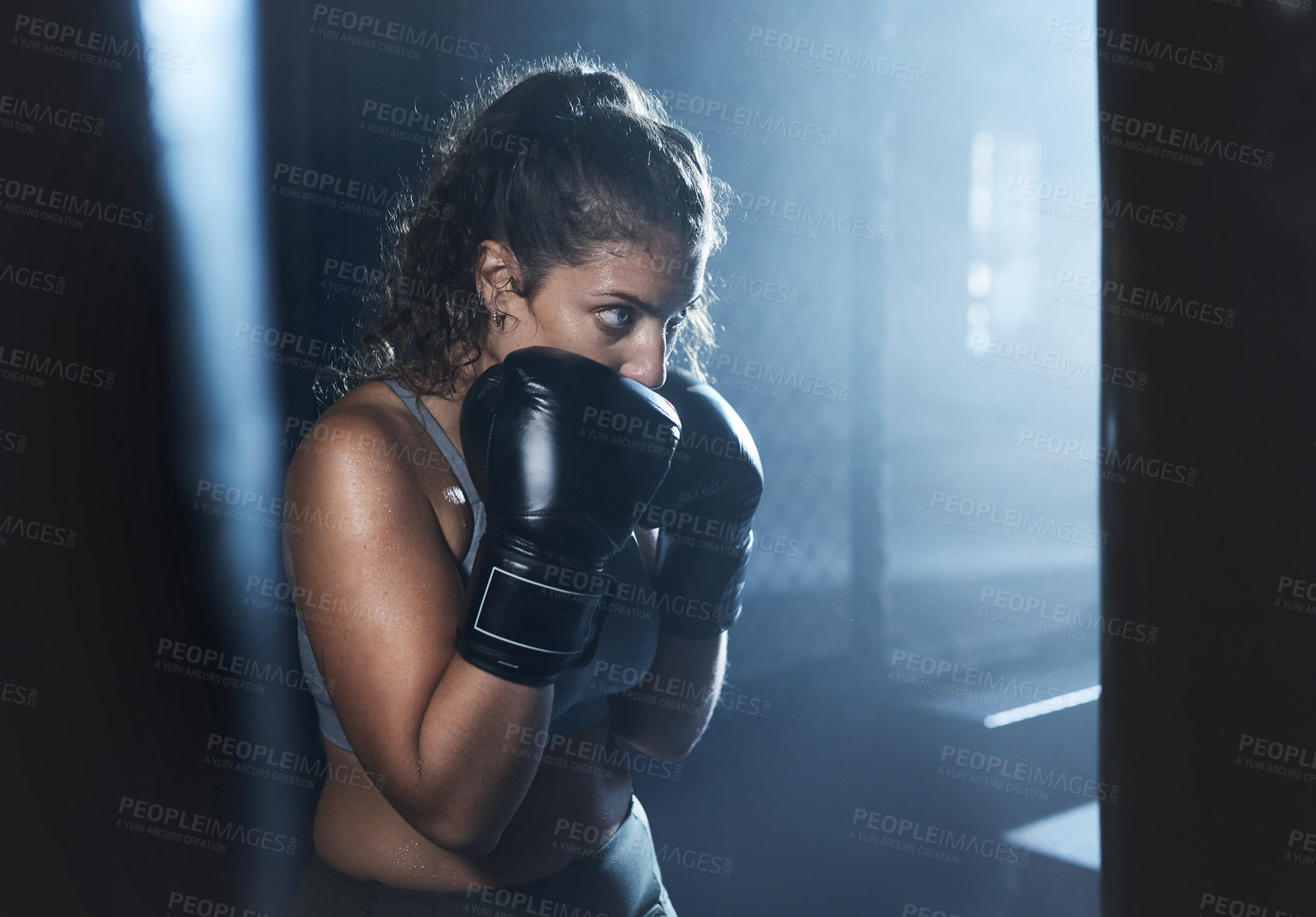 Buy stock photo Shot of a sporty young woman boxing in a gym