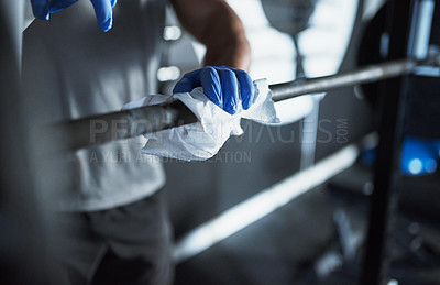 Buy stock photo Cropped shot of an unrecognisable man disinfecting the surfaces in a gym