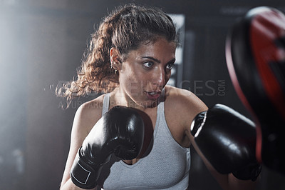Buy stock photo Shot of a young woman practicing with her coach at a boxing gym