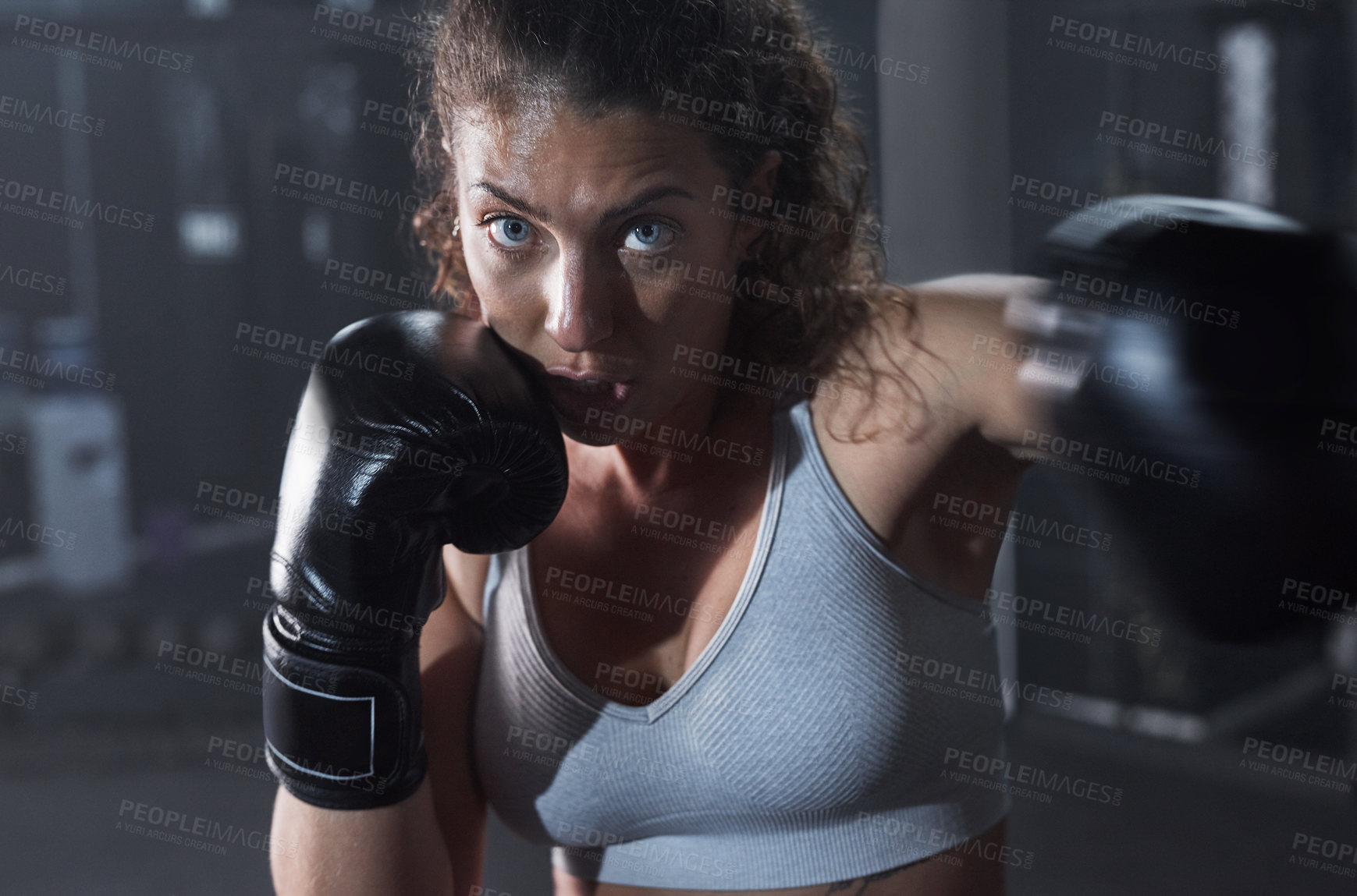 Buy stock photo Portrait of a young woman practicing her boxing routine at a gym