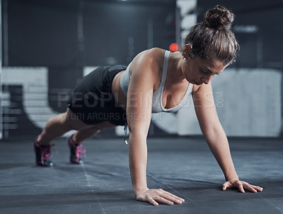 Buy stock photo Shot of a young woman doing push ups at a gym