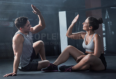 Buy stock photo Shot of a young man and woman giving each other a high five at the gym