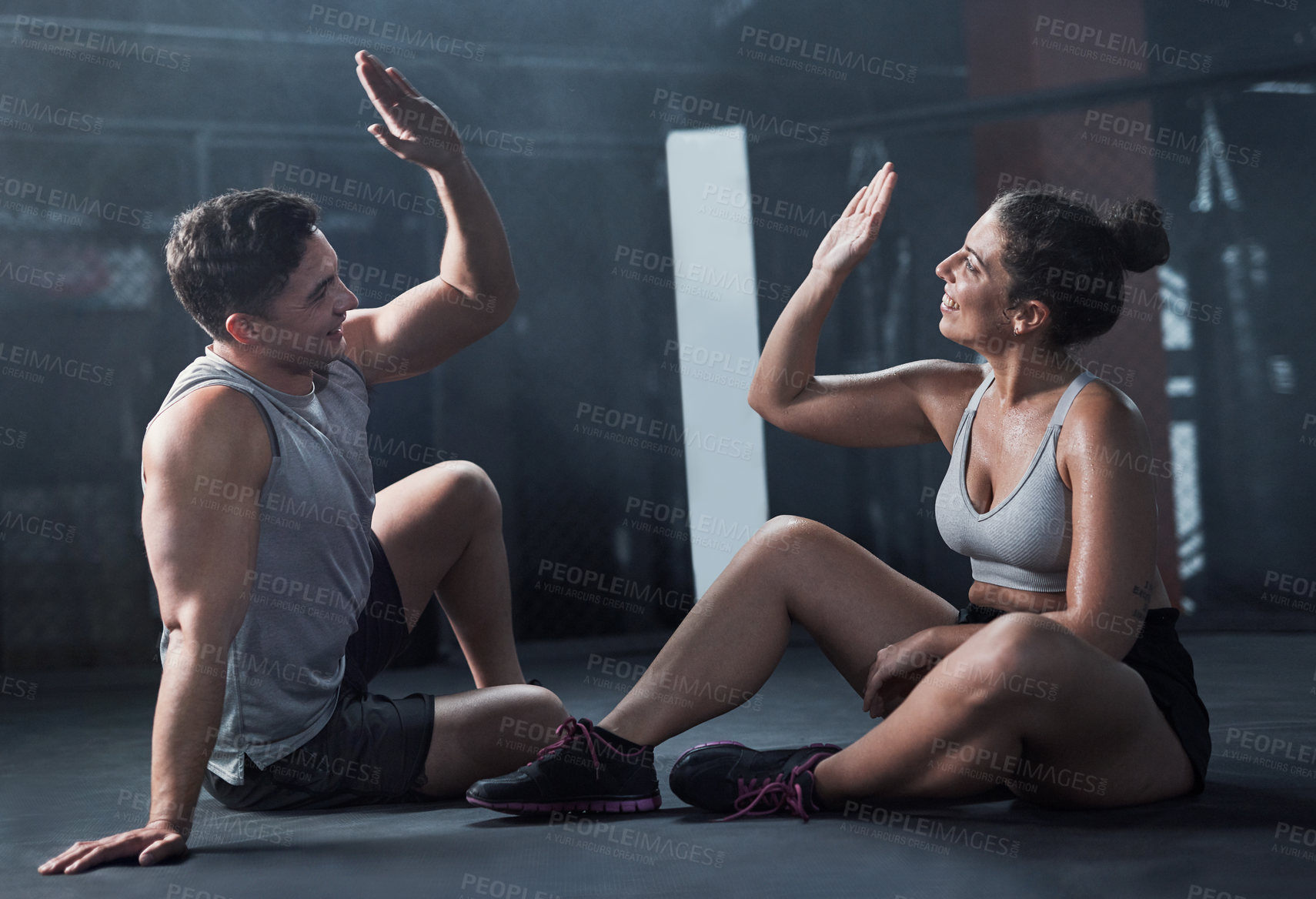 Buy stock photo Shot of a young man and woman giving each other a high five at the gym