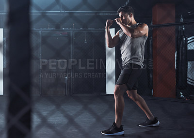 Buy stock photo Shot of a young man practicing his kickboxing routine at a gym