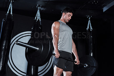 Buy stock photo Shot of a young man lifting a barbell during his workout at a gym