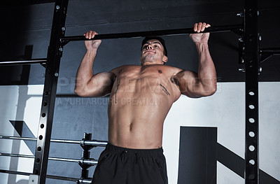 Buy stock photo Shot of a young man lifting doing pull ups at a gym