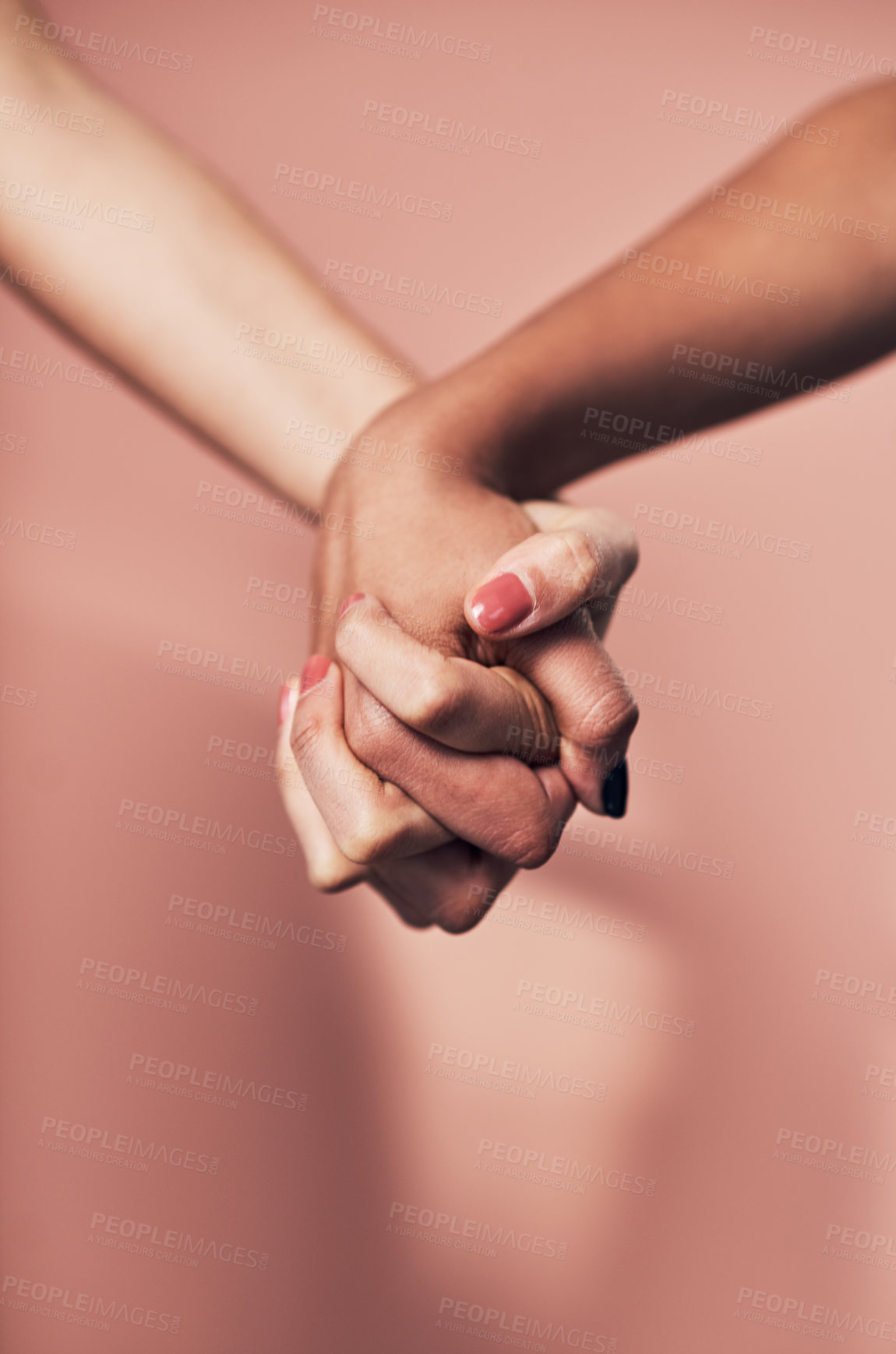 Buy stock photo Shot of two unrecognizable women holding hands against a pink background