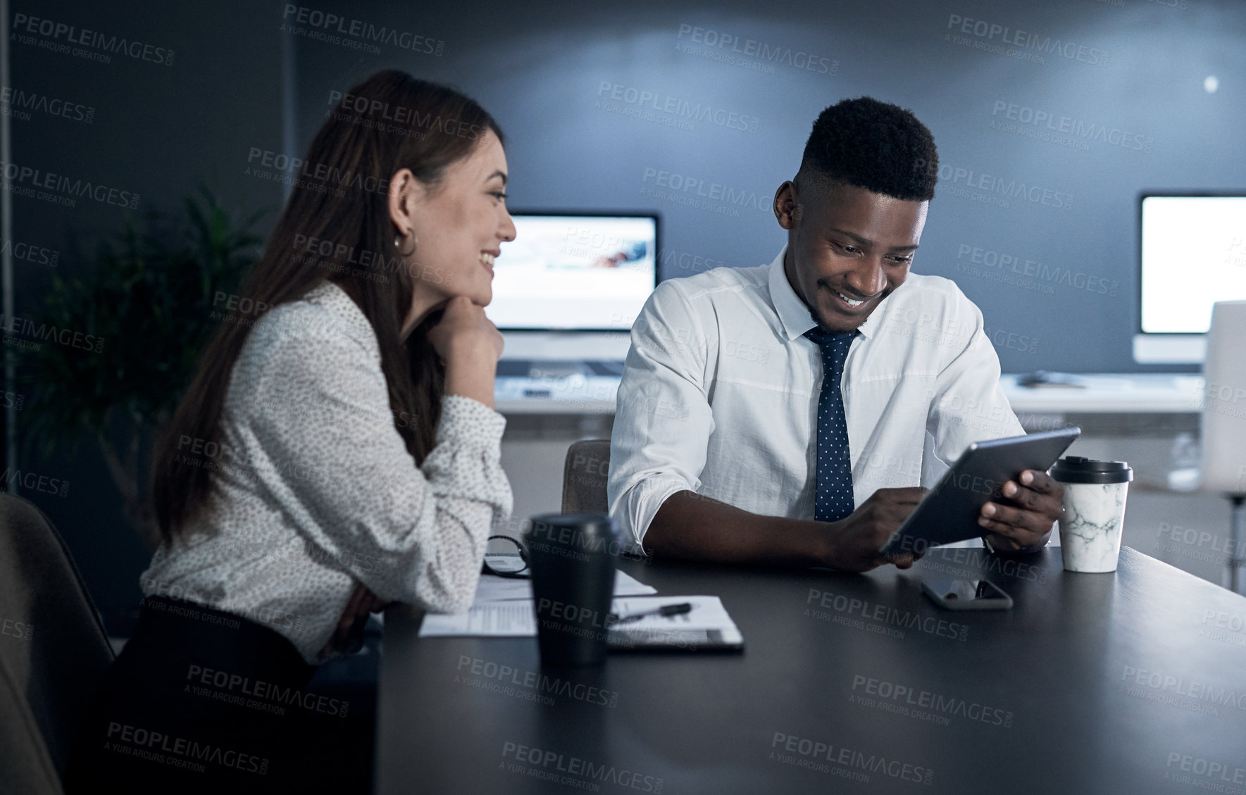 Buy stock photo Shot of two businesspeople working together in an office at night