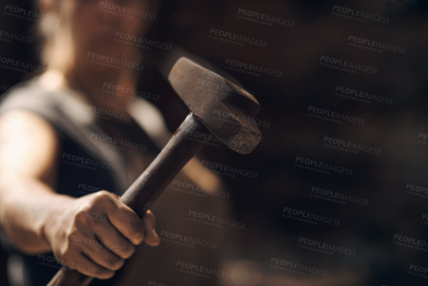 Buy stock photo Cropped shot of a woman holding a hammer while working at a foundry
