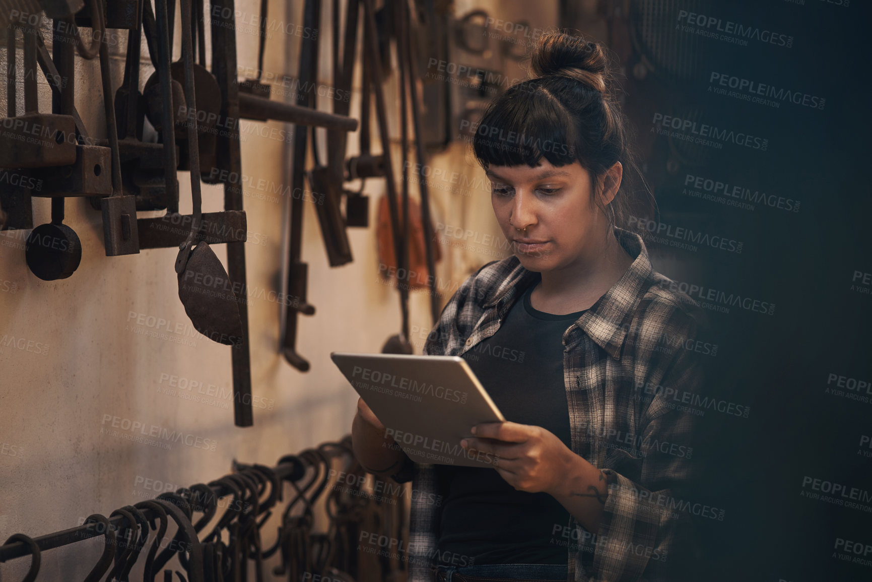 Buy stock photo Shot of a young woman using a digital tablet while working at a foundry