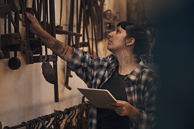 Buy stock photo Shot of a young woman using a digital tablet while working at a foundry