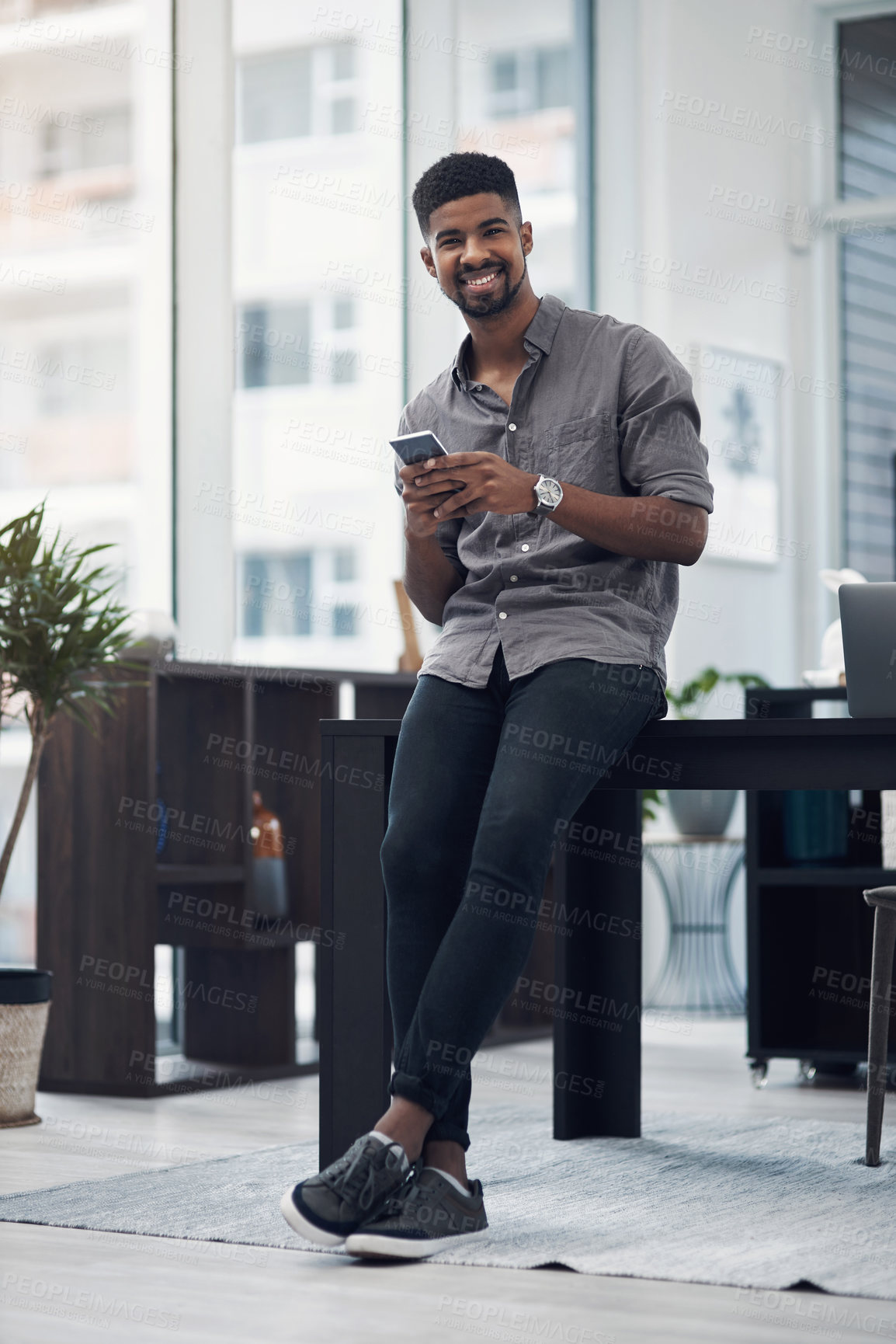 Buy stock photo Portrait of a young businessman using a cellphone in an office