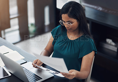 Buy stock photo Shot of a young businesswoman going through paperwork in an office