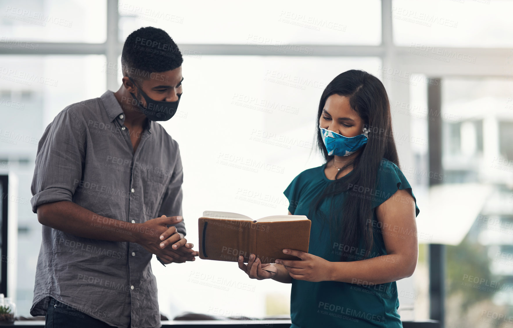 Buy stock photo Shot of two businesspeople wearing face masks while having a discussion in an office