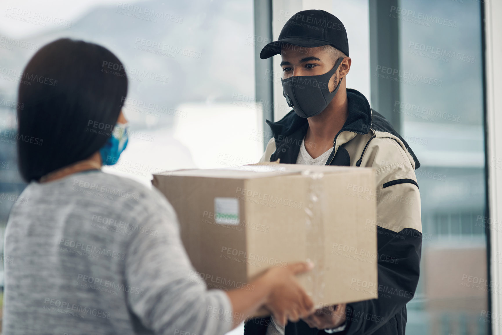 Buy stock photo Shot of a masked young woman receiving a delivery at home