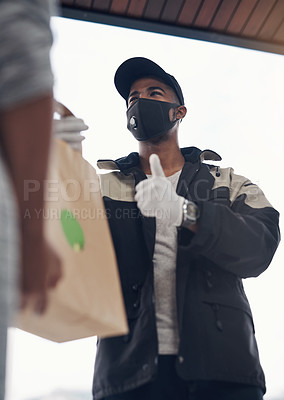 Buy stock photo Shot of a masked young man showing thumbs up while delivery takeout to a customer at home