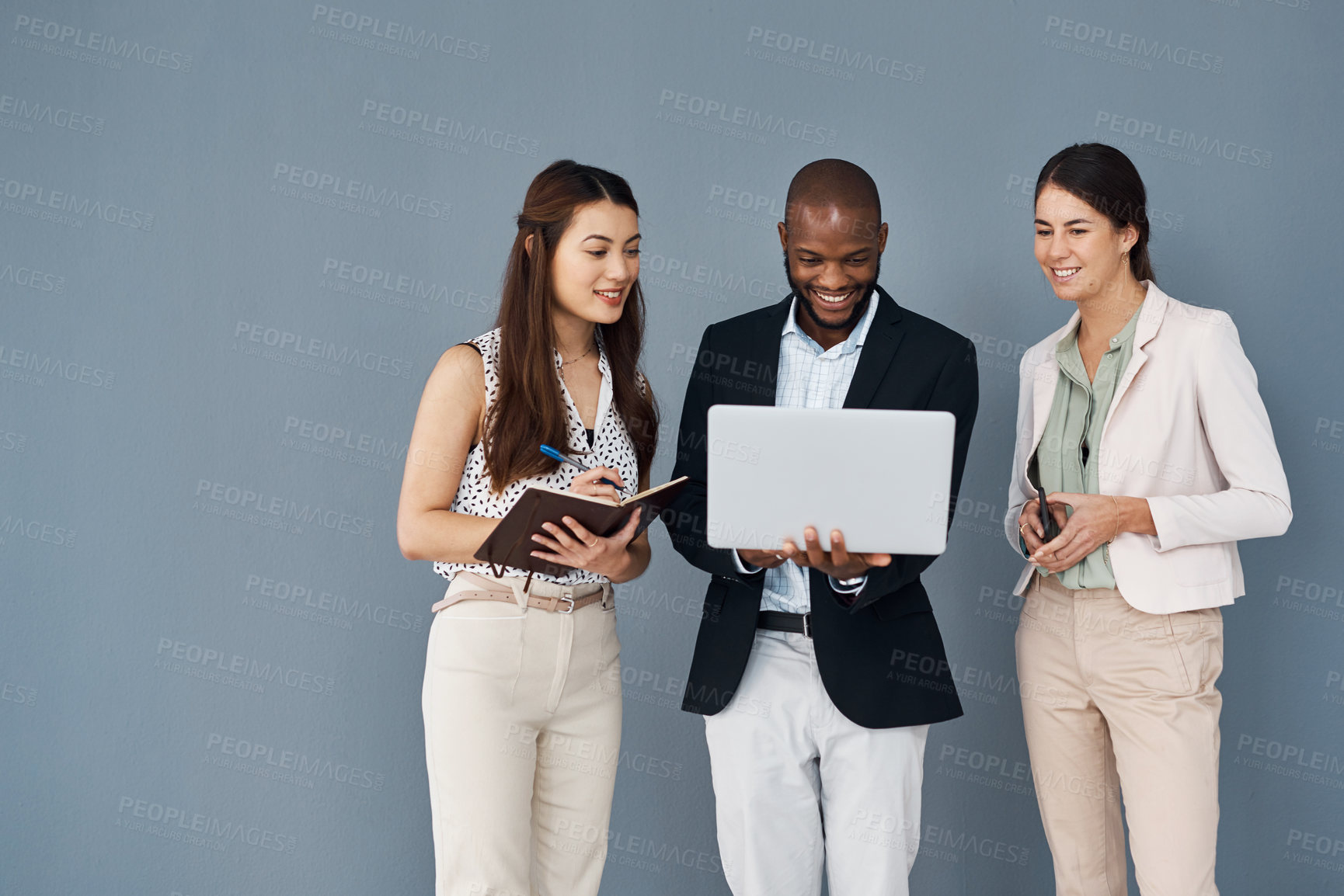 Buy stock photo Studio shot of a group of businesspeople using a laptop together against a grey background