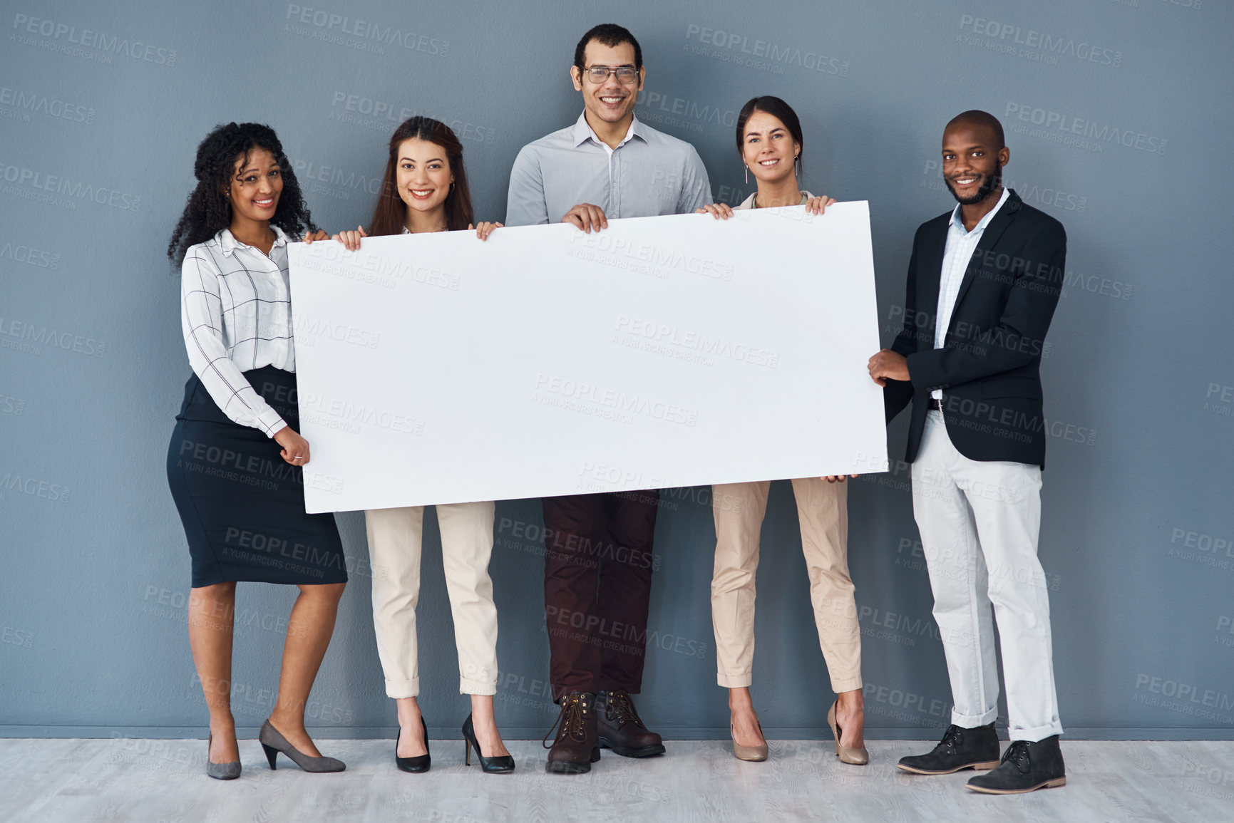 Buy stock photo Portrait of a group of businesspeople holding a black poster while standing against a grey background