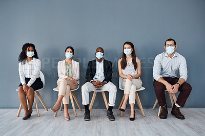 Buy stock photo Portrait of a group of businesspeople wearing face masks while sitting in line against a grey background