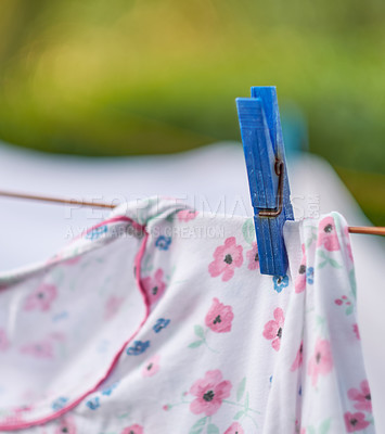 Buy stock photo Clothespin holding up laundry on a line outside. A clothing pin or peg is a useful tool to hang up clothes outside to dry and symbolizes housework and chores. Closeup of a shirt on a washing line