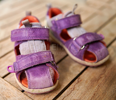 Buy stock photo Top view of purple baby shoes on a table at home from above. Little girl footwear symbolizing new life, beginnings and pregnancy. Small stylish and fashionable sandals of a playful child on a desk