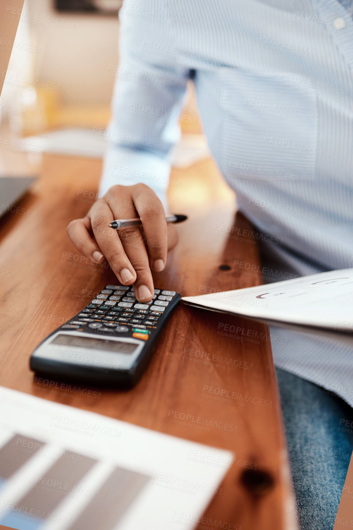 Buy stock photo Cropped shot of a businesswoman using a calculator while going over financial paperwork at her desk