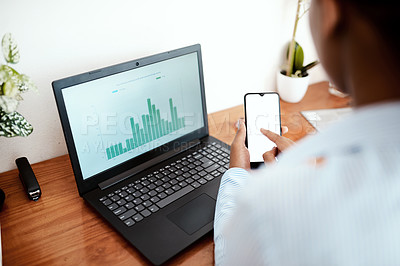 Buy stock photo Cropped shot of a businesswoman using a laptop and smartphone while analysing financial data at her desk