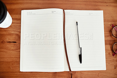 Buy stock photo Shot of a notebook and pen on a desk in an office