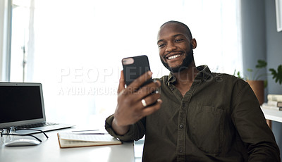 Buy stock photo Shot of a young businessman using a smartphone at his desk in a modern office