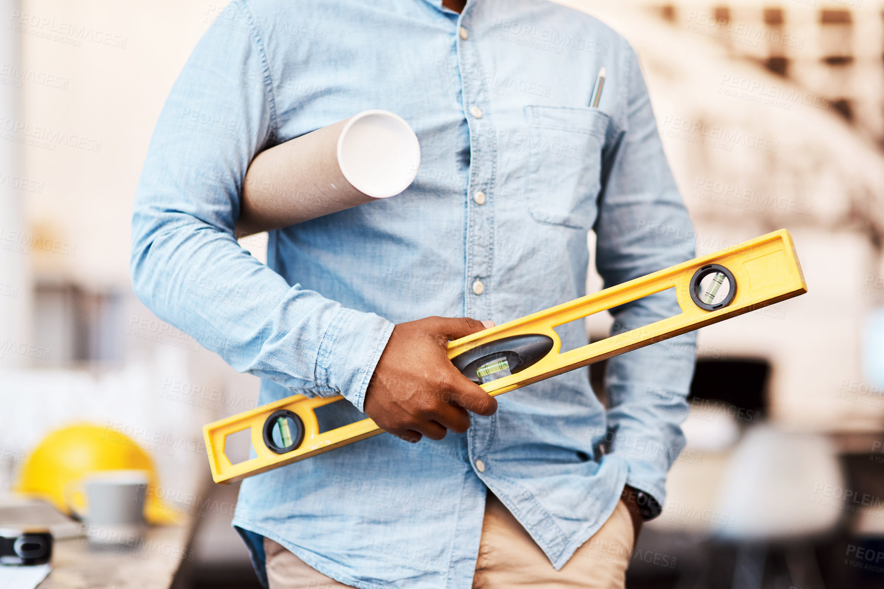 Buy stock photo Shot of an unrecognisable man holding a blueprint and spirit level in a modern office