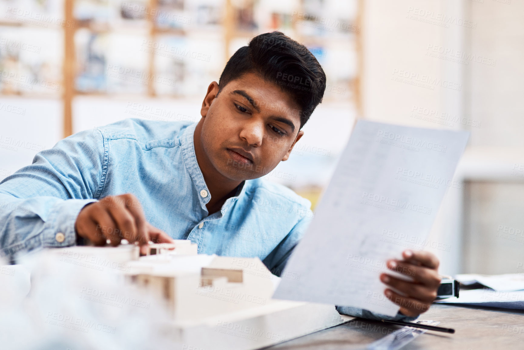 Buy stock photo Shot of a young architect designing a building model in a modern office