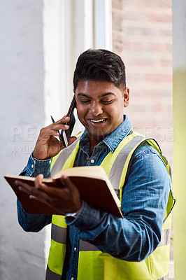 Buy stock photo Shot of a engineer talking on his cellphone while looking at his notebook