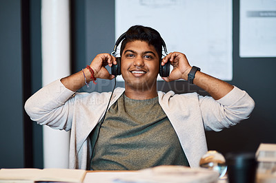 Buy stock photo Portrait of a young architect using headphones while working in a modern office