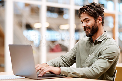 Buy stock photo Shot of a young businessman working on a laptop in an office