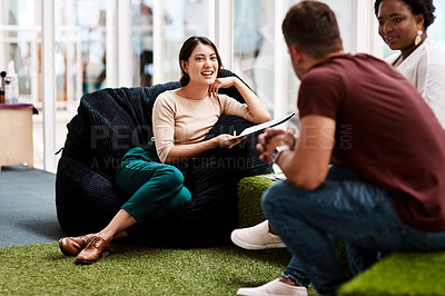 Buy stock photo Shot of a young businesswoman having a discussion with her colleagues while sitting on a beanbag in an office
