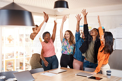 Buy stock photo Cropped shot of a group of young designers raising their hands in celebration while standing in the boardroom of their office