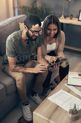 Buy stock photo Shot of a young couple sing a digital tablet while going through paperwork at home