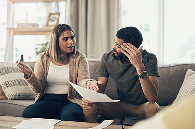 Buy stock photo Shot of a young couple having an argument while going over paperwork at home