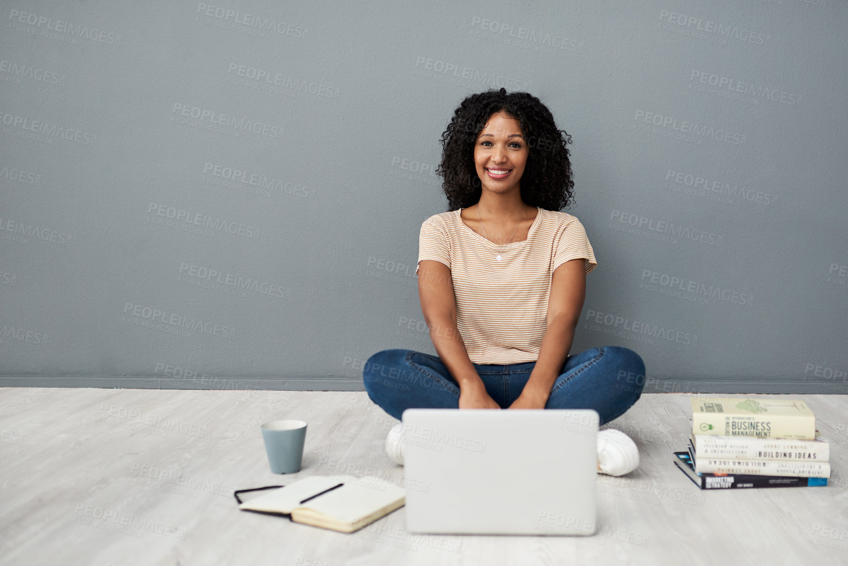 Buy stock photo Studio shot of a young woman using a laptop while completing her studies against a gray background
