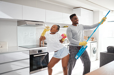 Buy stock photo Shot of a happy young couple having fun while cleaning the kitchen at home