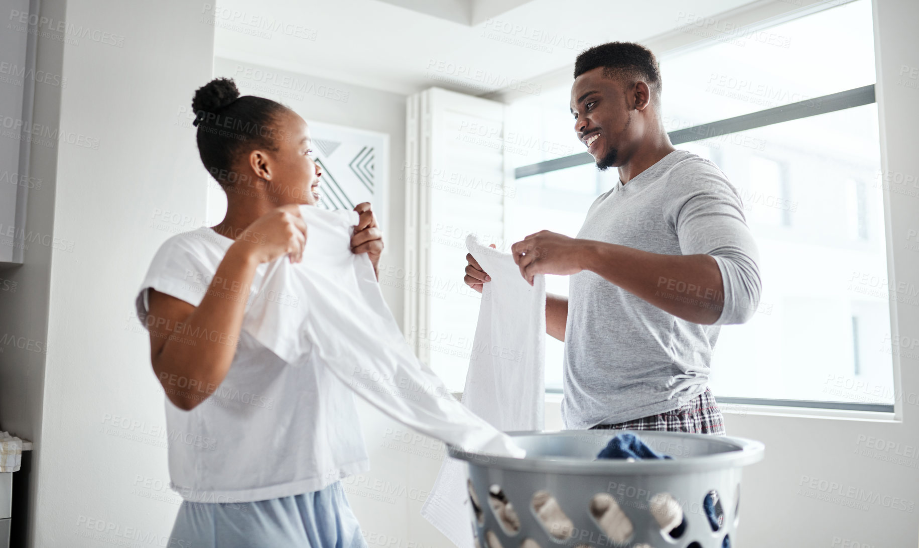 Buy stock photo Shot of a happy young couple doing laundry together at home