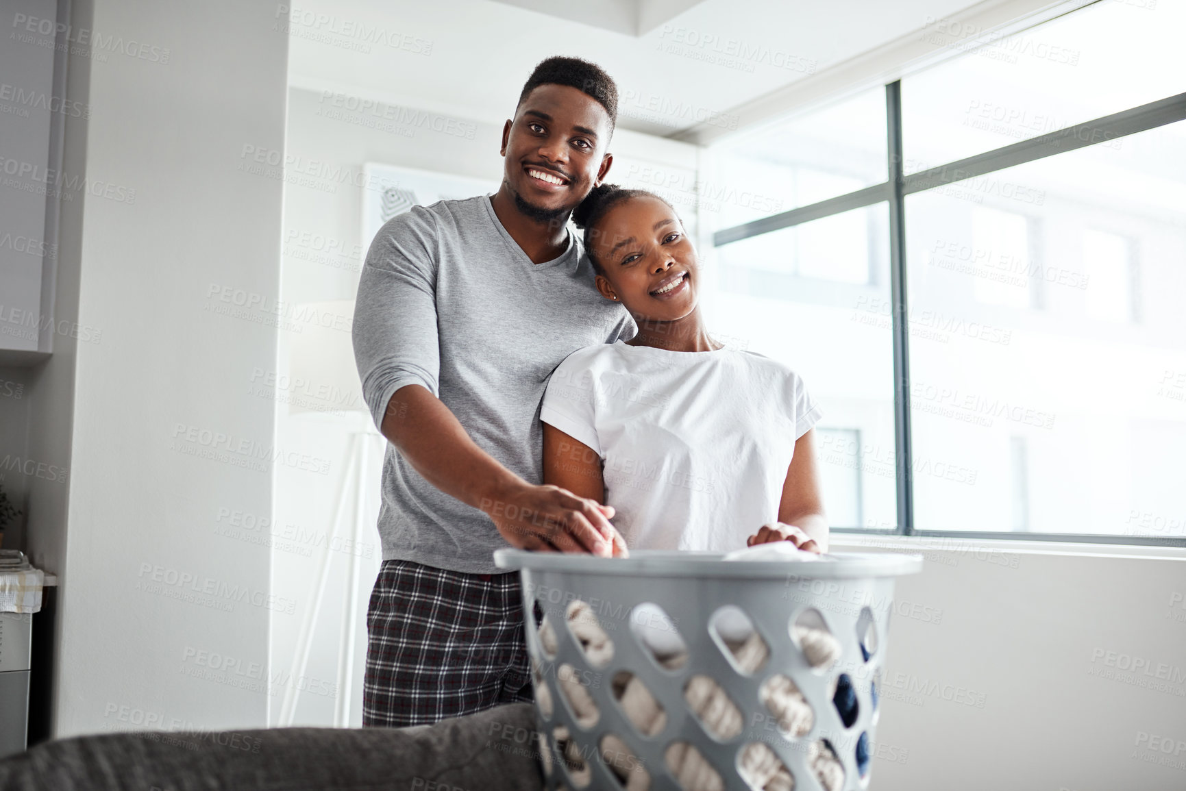 Buy stock photo Shot of a happy young couple doing laundry together at home