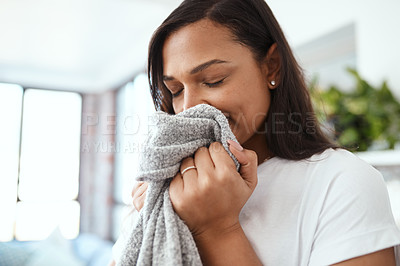 Buy stock photo Shot of a young woman smelling clean laundry at home
